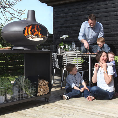 Morso Forno Garden ensemble sur la terrasse. Le four à pizza Forno posé sur la table de 120cm noir sur roulettes