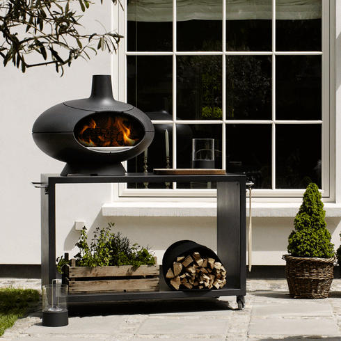 Le four Forno allumé sur la table noir de 120cm. Une belle ensemble Forno Garden dans le jardin. 
